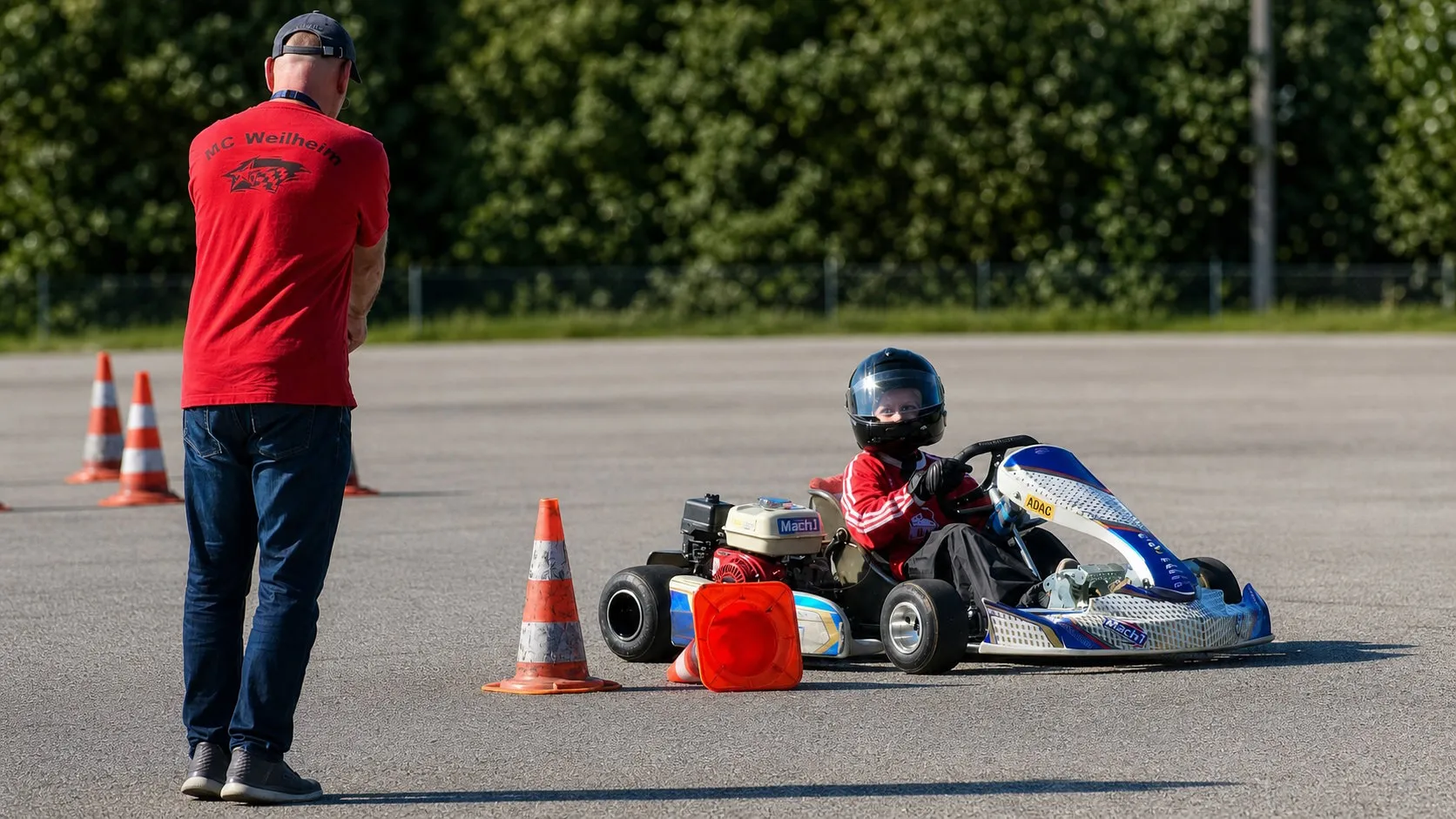Trainer steht neben einem jungen Piloten auf der Strecke